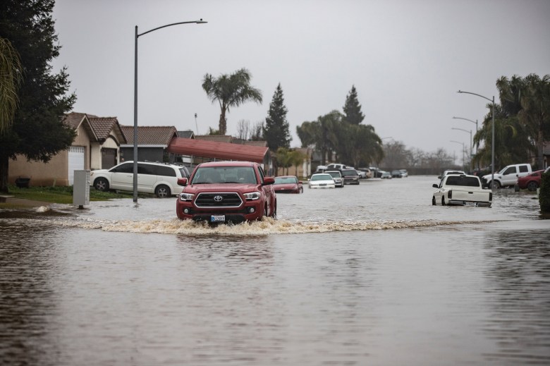 Residents in a Planada drive through a flooded neighborhood on Jan. 11, 2023. The town was under evacuation orders after a series of storms flooded the area. Photo by Larry Valenzuela, CalMatters/CatchLight Local