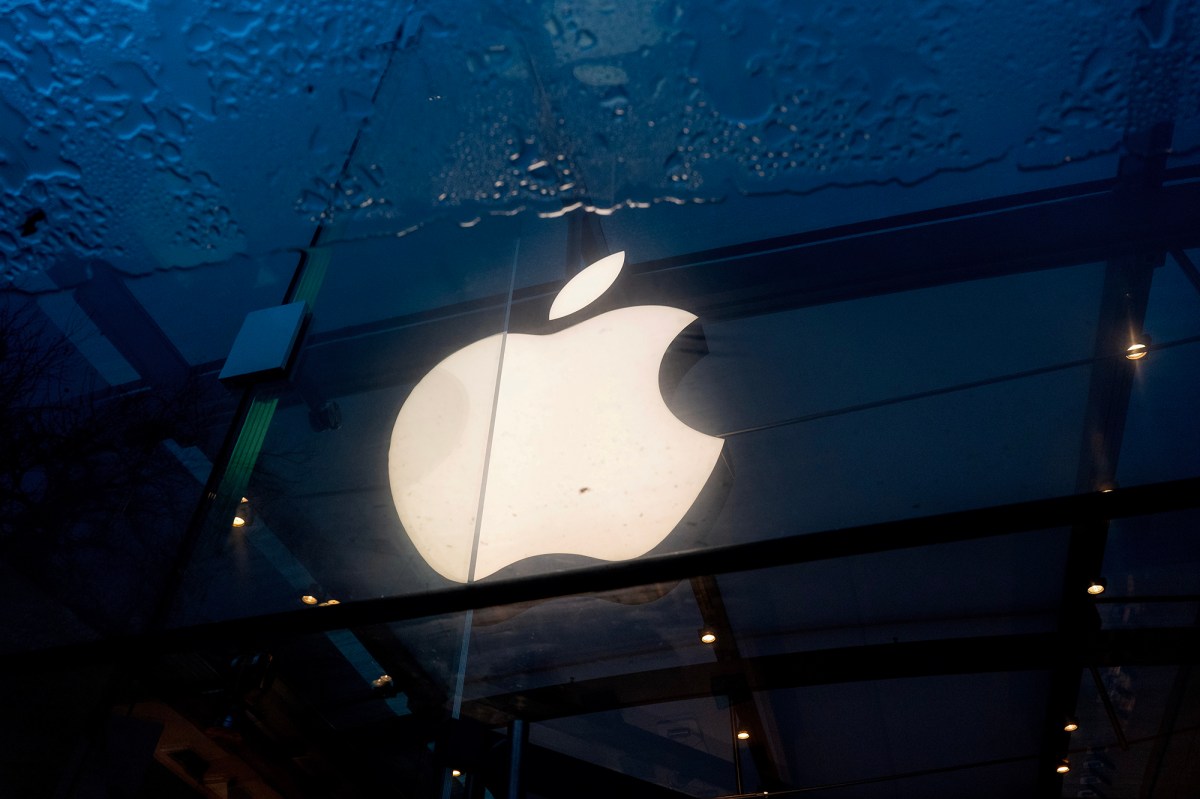 A bright and lit Apple logo is reflected in a puddle of water.