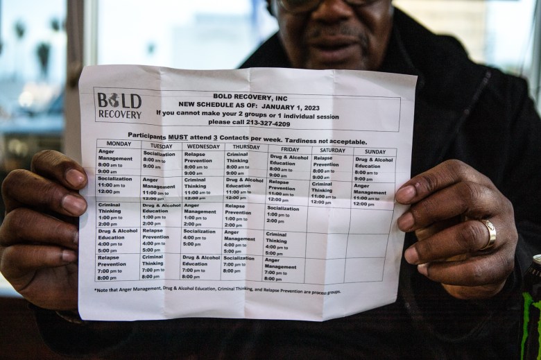 Eugene Lewis holds up a schedule of classes he takes in Los Angeles on Feb. 2, 2023. Lewis attends a certain number of classes as part of his rehabilitation program. Photo by Larry Valenzuela, CalMatters/CatchLight Local