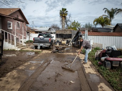 A Cutler resident shovels mud off his driveway on March 12, 2023. The area flooded after a levee was breached during a series of storms that hit the Central Valley.