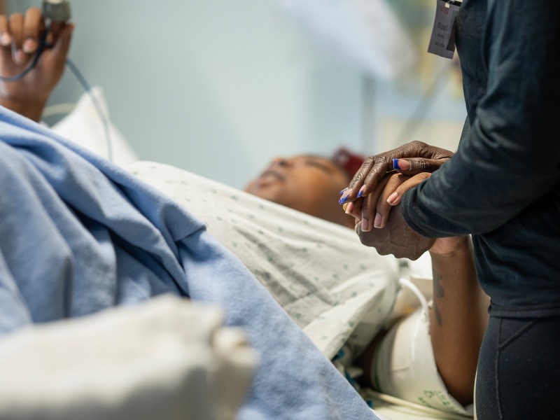 Latrina Jackson, the mother of Detranay Blankenship, holds her hand as she is about to give birth for the first time at Martin Luther King Community Hospital in Los Angeles, on March 22, 2024. Photo by Jules Hotz for CalMatters