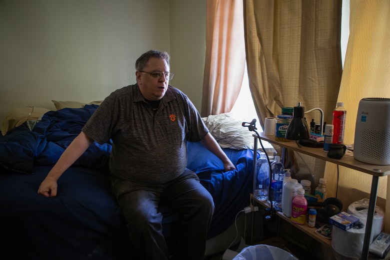 Stephen Mintz sits at the side of his bed in his apartment in Fresno on March 3, 2023. Mintz was diagnosed with COVID-19 in September and has had chronic fatigue since then. Photo by Larry Valenzuela, CalMatters/CatchLight Local