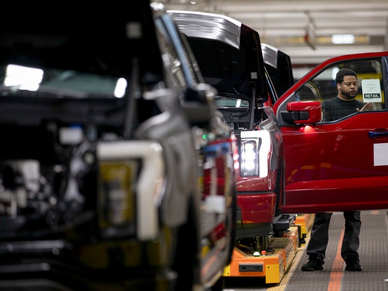 A worker adds a retail sign to an electric Ford F-150 Lightning on the assembly line at the Ford River Rouge complex in Dearborn, Michigan on April 4, 2023. Photo by Emily Elconin for CalMatters