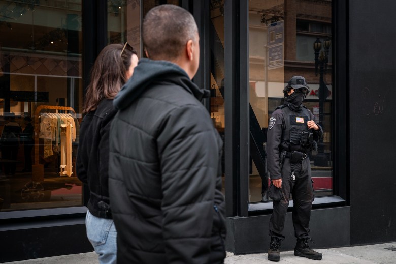 A security guard stands by the front entrance of a luxury retail storefront in downtown San Francisco on April 15, 2024. Retail theft has plagued the area, and numerous storefronts sit vacant. Photo by Loren Elliott for CalMatters