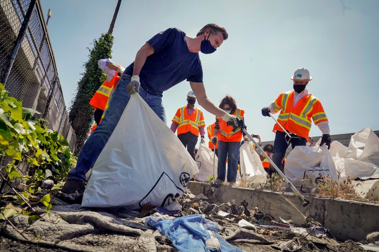 Gov. Gavin Newsom joins a cleanup effort in Los Angeles on May 11, 2021. Newsom proposed $12 billion in new funding to get more people experiencing homelessness in the state into housing and to "functionally end family homelessness" within five years. AP Photo/Marcio Jose Sanchez