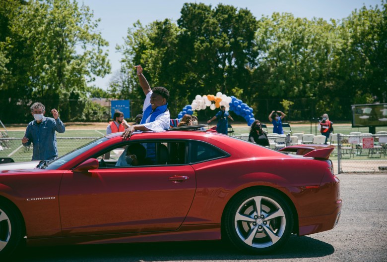 Sir cheers from the sunroof of a car while driving away to make room for the following commencement ceremony at Madison Park Academy on May 21, 2021. Photo by Marissa Leshnov for CalMatters