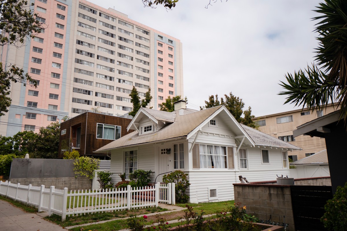 A high-rise apartment tower stands behind single-family homes near Wilshire Boulevard and 6th Street in Santa Monica on May 24, 2023. Photo by Zaydee Sanchez for CalMatters