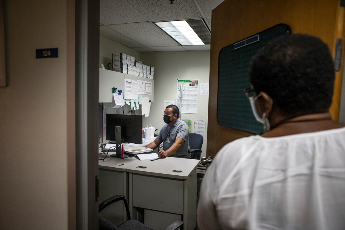 STD Investigator Hou Vang (left) works in his office as Jena Adams (right), Communicable Disease Program Manager, checks in on him on June 8, 2022. Photo by Larry Valenzuela, CalMatters/CatchLight Local