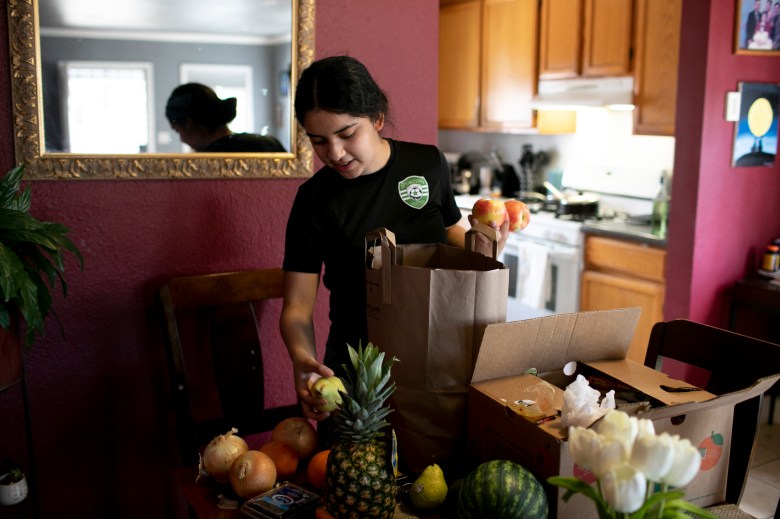 Claudeth unpacks free groceries and meals delivered by Oakland Unified School District. Photo by Anne Wernikoff, CalMatters