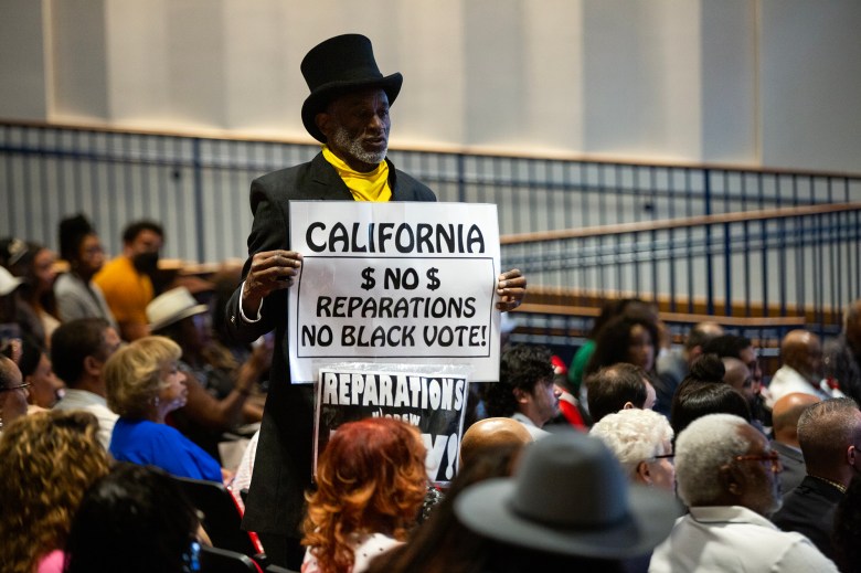 Morris Griffin holds up a sign at the Reparations Task Force hearing at the March Fong Eu Secretary of State offices in Sacramento on June 29, 2023. Photo by Semantha Norris, CalMatters