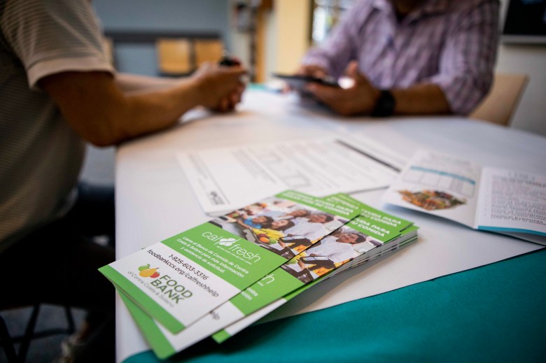 An outreach worker for the Food Bank of Contra Costa and Solano helps a person fill out an application for CalFresh, the state's food stamp program. Photo by Anne Wernikoff, CalMatters