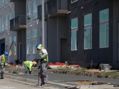 Decked in safety gear, a construction crew works with concrete for a sidewalk in Fremont.