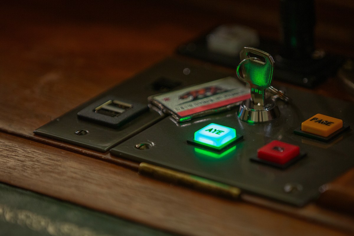 A close-up of a key with a California flag keychain on a voting panel with the "Aye" vote button lite up in green on a legislator's desk on the Assembly floor at the state Capitol in Sacramento on Aug. 17, 2023. Photo by Semantha Norris, CalMatters