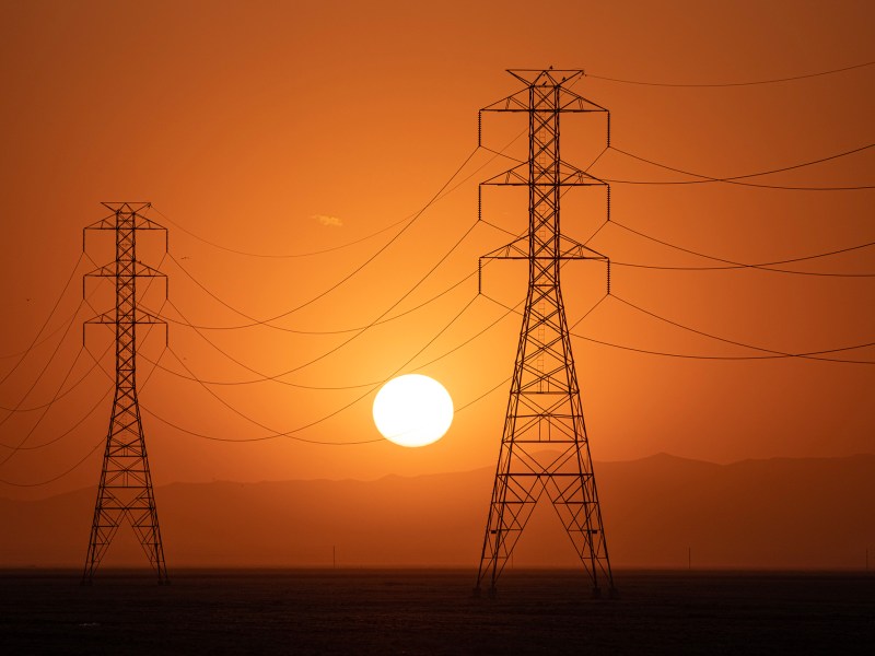 The sun sets behind a row of electrical towers in Fresno County on Sept. 6, 2022. Photo by Larry Valenzuela, CalMatters/CatchLight Local