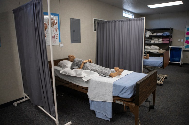 A workstation with a bed and a nursing dummy in a classroom.