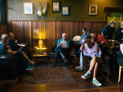 Attendees gather in chairs and couches at a bar while reading flyers with information on ballot propositions.