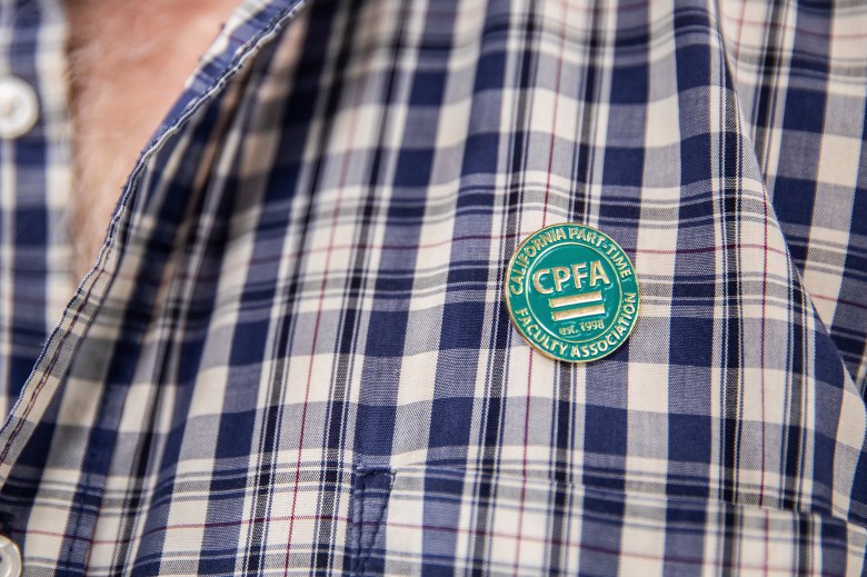 A close-up photo of a circular faculty pin pinned to a plaid shirt.