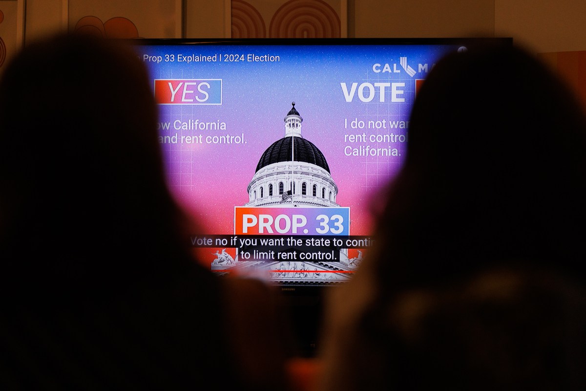 A view people looking at a monitor displaying a video with information on Prop. 33 at a voter information event.