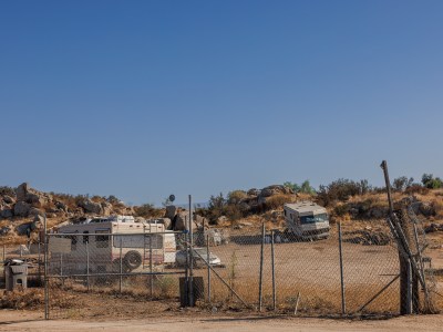 View of a trailer community on an unpaved road inside a fenced in area.