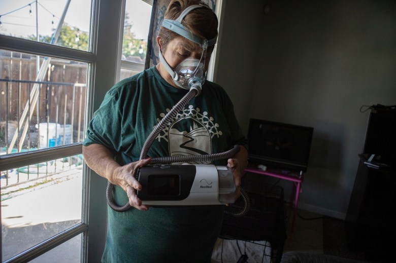 Maria Arevalo shows the CPAP mask she has to wear every night in her daughters home in Visalia on Oct. 10, 2023. Arevalo, who has lived in Pixley for 47 years, says the chemicals given off from the dairy has affected her breathing. Photo by Larry Valenzuela, CalMatters/CatchLight Local