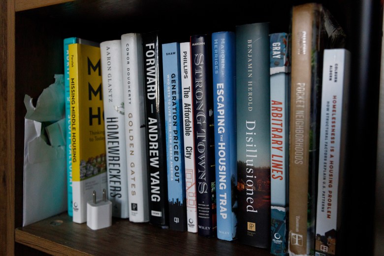 Various books on housing issues line a bookshelf at a home.