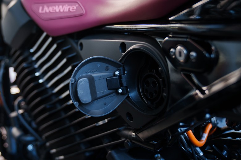 A charging port with the lid open from an electric motorcycle.