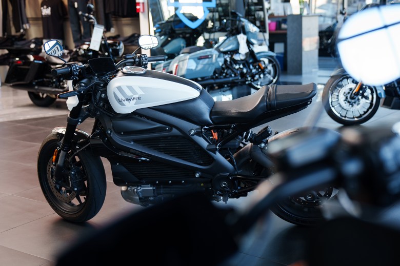 An electric motorcycle in the showroom of a motorcycle dealership with other motorcycles.