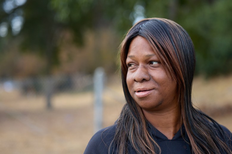 A close-up view of a person with black and brown highlighted hair and a black hoodie as they loo to their right.