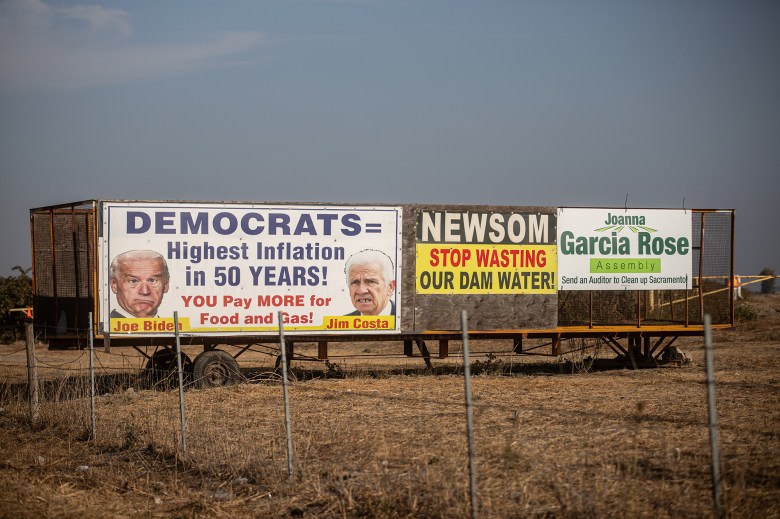 A trailer with the election-related signs posted on it. The first sign reads "Democrats = highest Inflation in 50 years!", "You pay more for food and gas!" with photos of politicians Joe Biden and Jim Costa. A second sign reads "Newsom stop wasting our dam water." And the third sign reads" Joanna Garcias Rose Assembly."