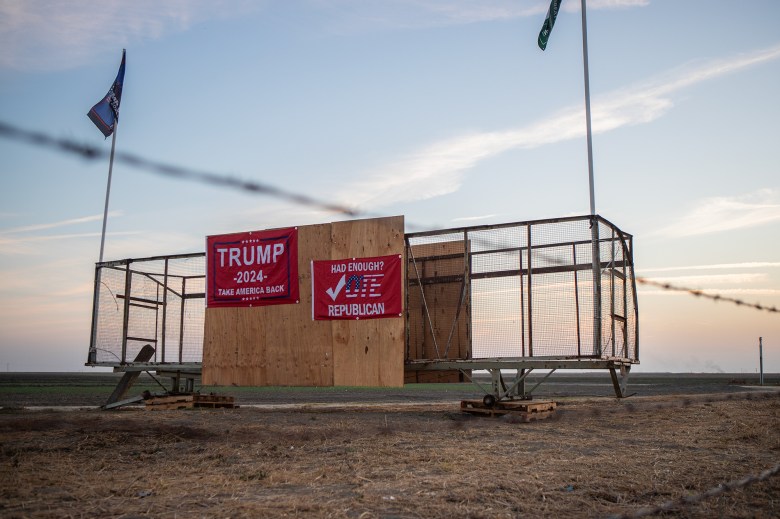 Two red signs that read "Trump 2024 Take American Back" and "Had Enough? Vote Republican?" are hung up on the side of a trailer near a highway.