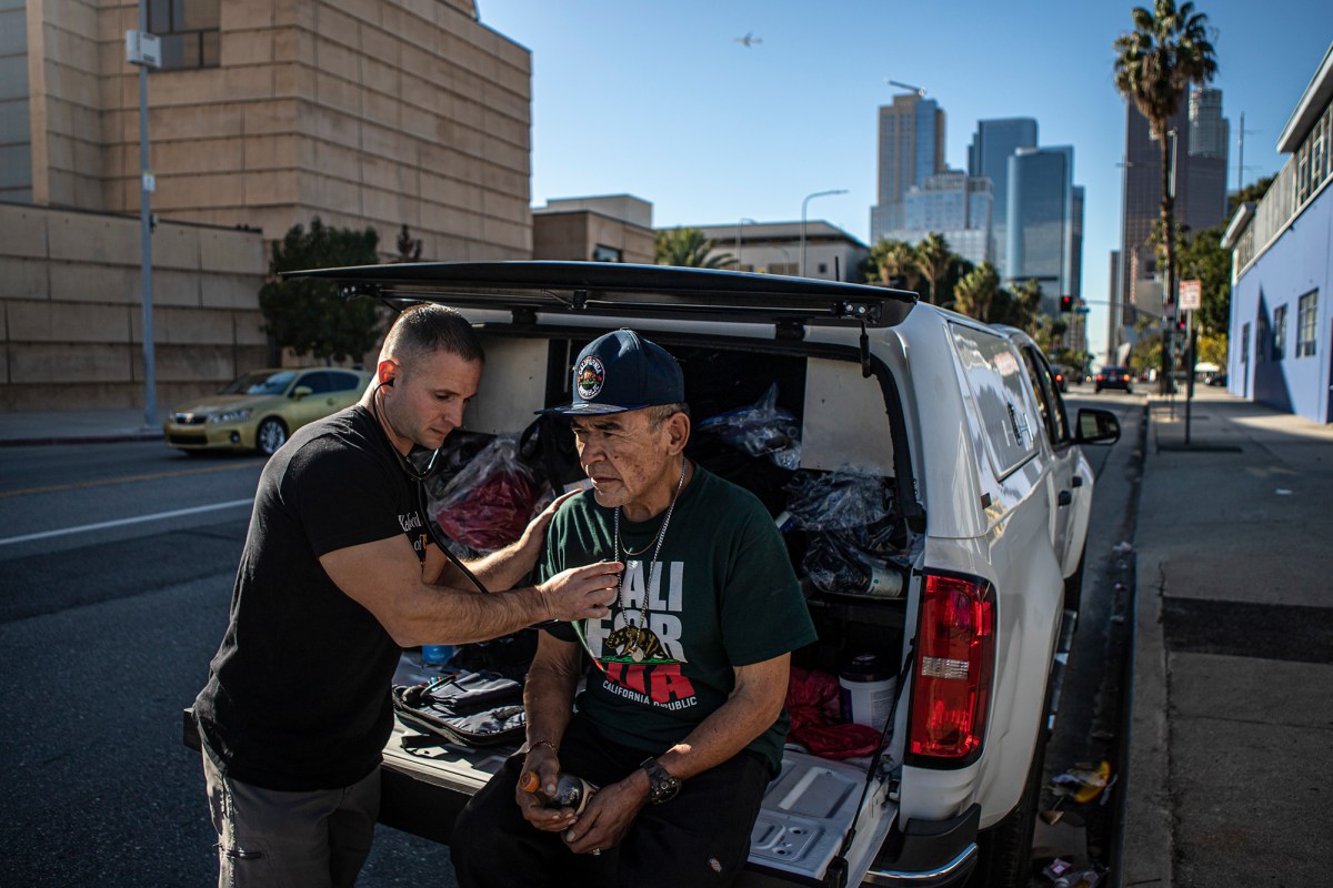 Physician's assistant Brett Feldman does a checkup on his patient Gary Dela Cruz on the side of the road near his encampment in downtown Los Angeles on Nov. 18, 2022. Feldman is the director and co-founder of Street Medicine at the Keck School of Medicine at the University of Southern California.Photo by Larry Valenzuela for CalMatters