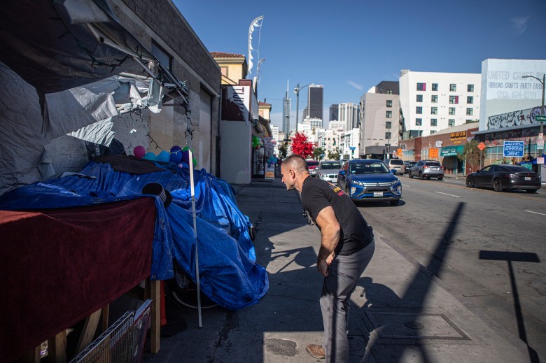 Physician's assistant Brett Feldman asks a man in his encampment if he has seen a patient along Skid Row on Nov. 18, 2022. The patient was likely pushed out of the area as the Los Angeles sanitation department clear out the unhoused to clean the street near Skid Row. Photo by Larry Valenzuela for CalMatters