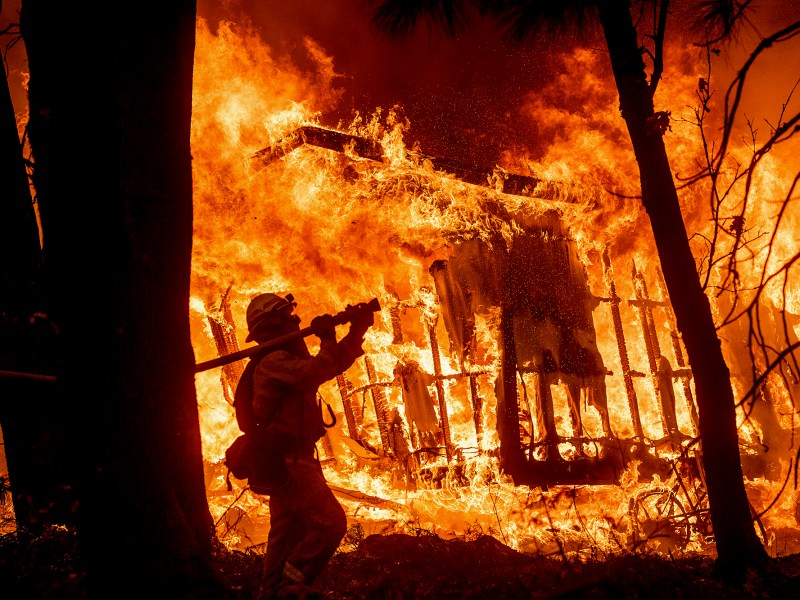 As wildfires intensify, thousands of overworked California firefighters carry a heavy load of trauma, pain and grief. Here, firefighter Jose Corona sprays water as flames from the Camp Fire consume a home in Magalia on Nov. 9, 2018. Photo by Noah Berger, AP Photo